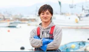 グレーのパーカーと作業着を着用した若い男性