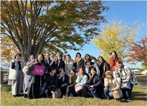 秋の屋外で笑顔で集合写真を撮る女性たち