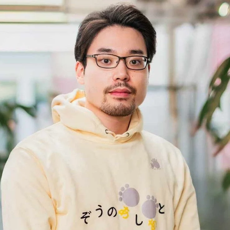 眼鏡をかけたヒゲのある男性がカメラを見つめているポートレート