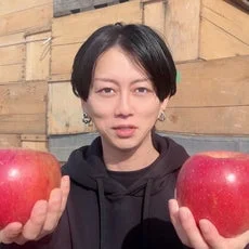 若い男性が両手に赤いりんごを持ってカメラを見つめています