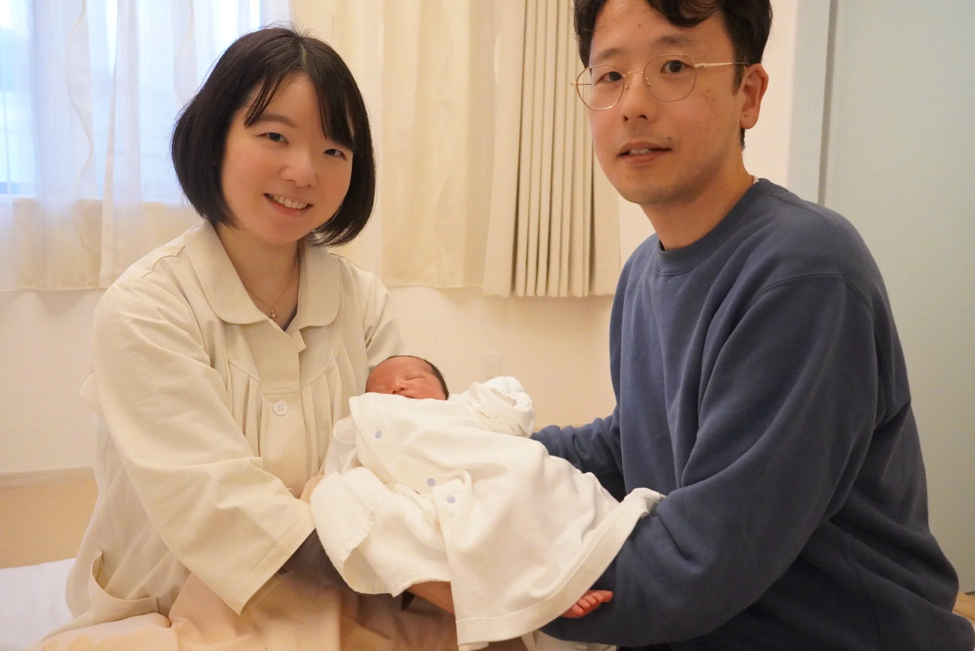 新生児を抱き笑顔の夫婦
