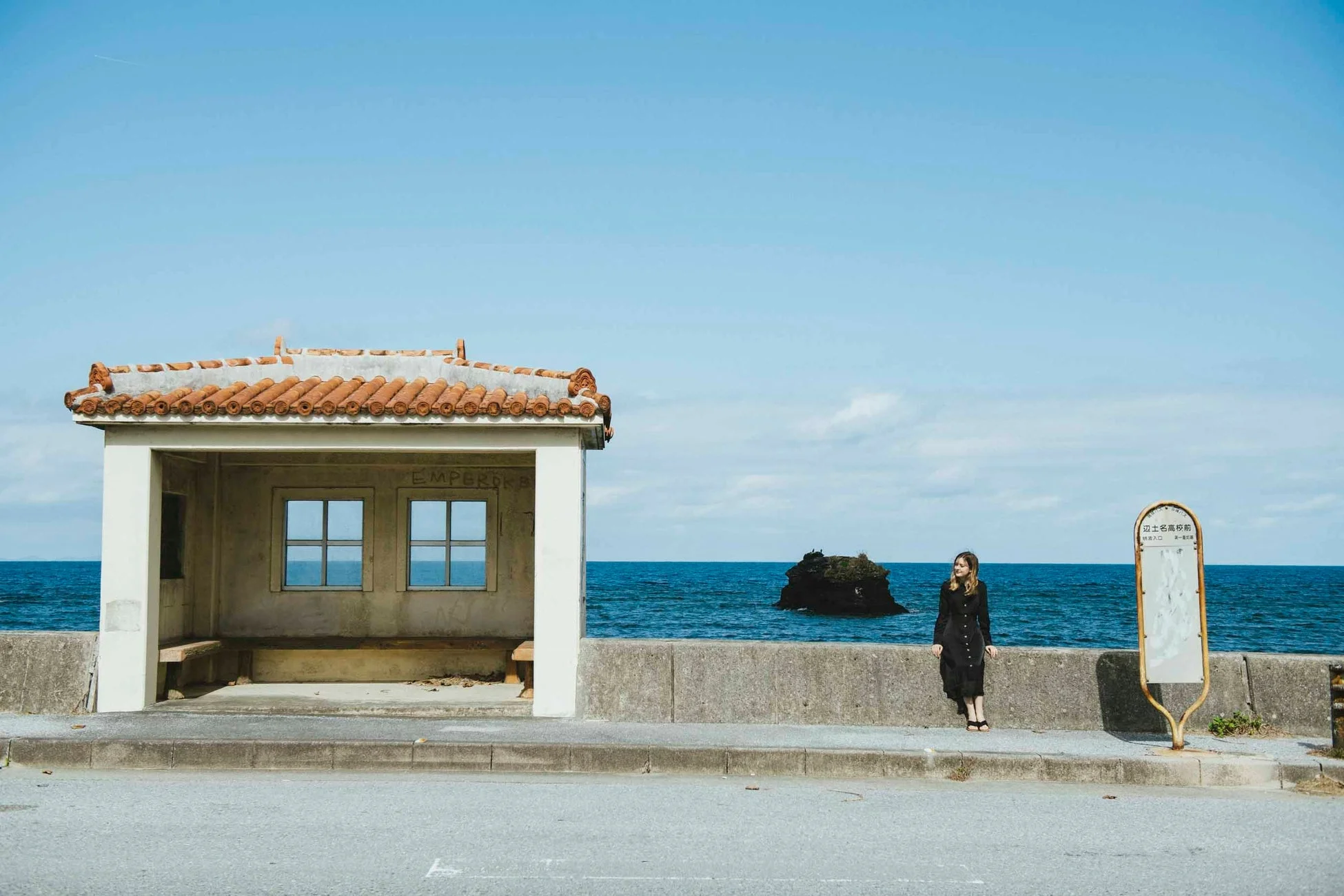 海岸沿いのバス停と女性