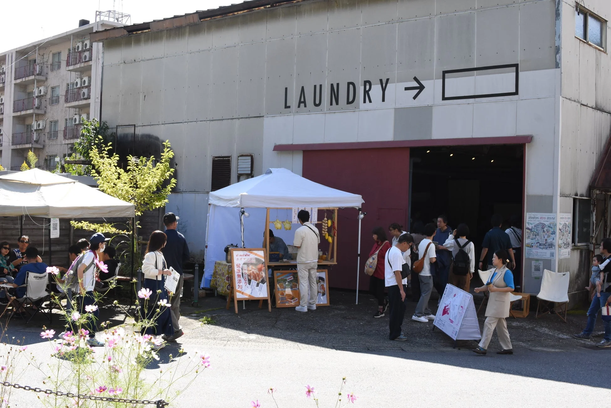 「LAUNDRY」と書かれた建物の前で賑わう屋外マーケット