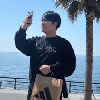 海辺でスマートフォンを操作する男性