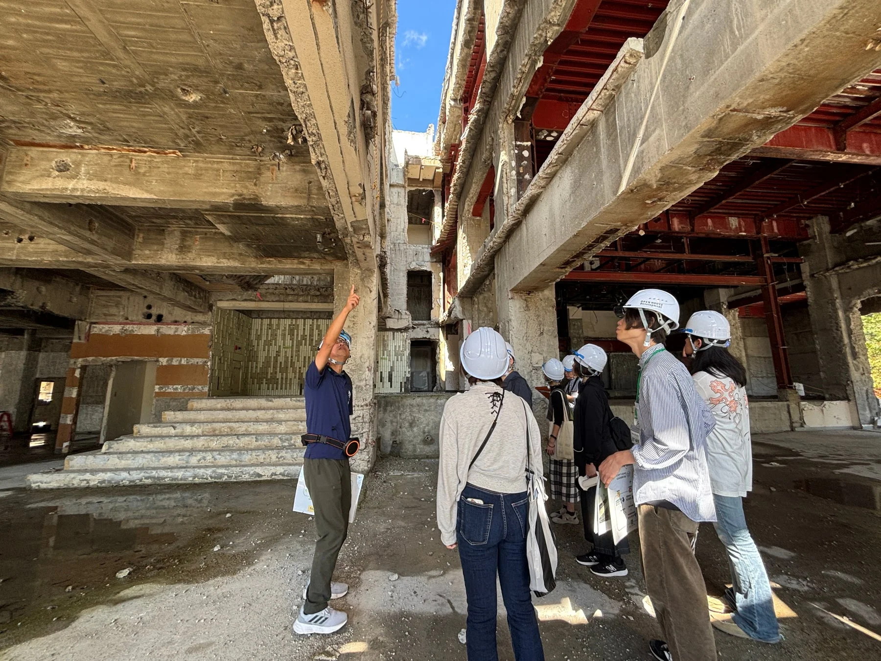 ヘルメット着用者が見学するコンクリート構造の建物