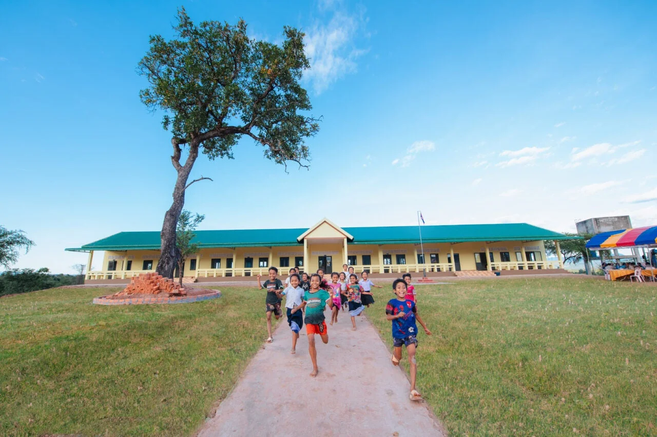 笑顔で走る子どもたちと学校の建物