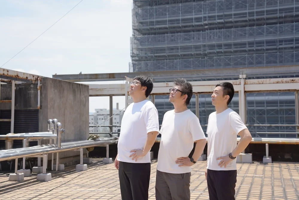 屋上で空を見上げる男性3人組