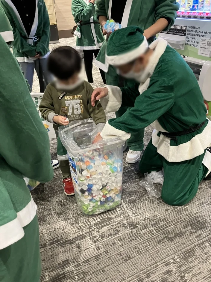 サンタと子供がペットボトルキャップ回収活動をしている様子