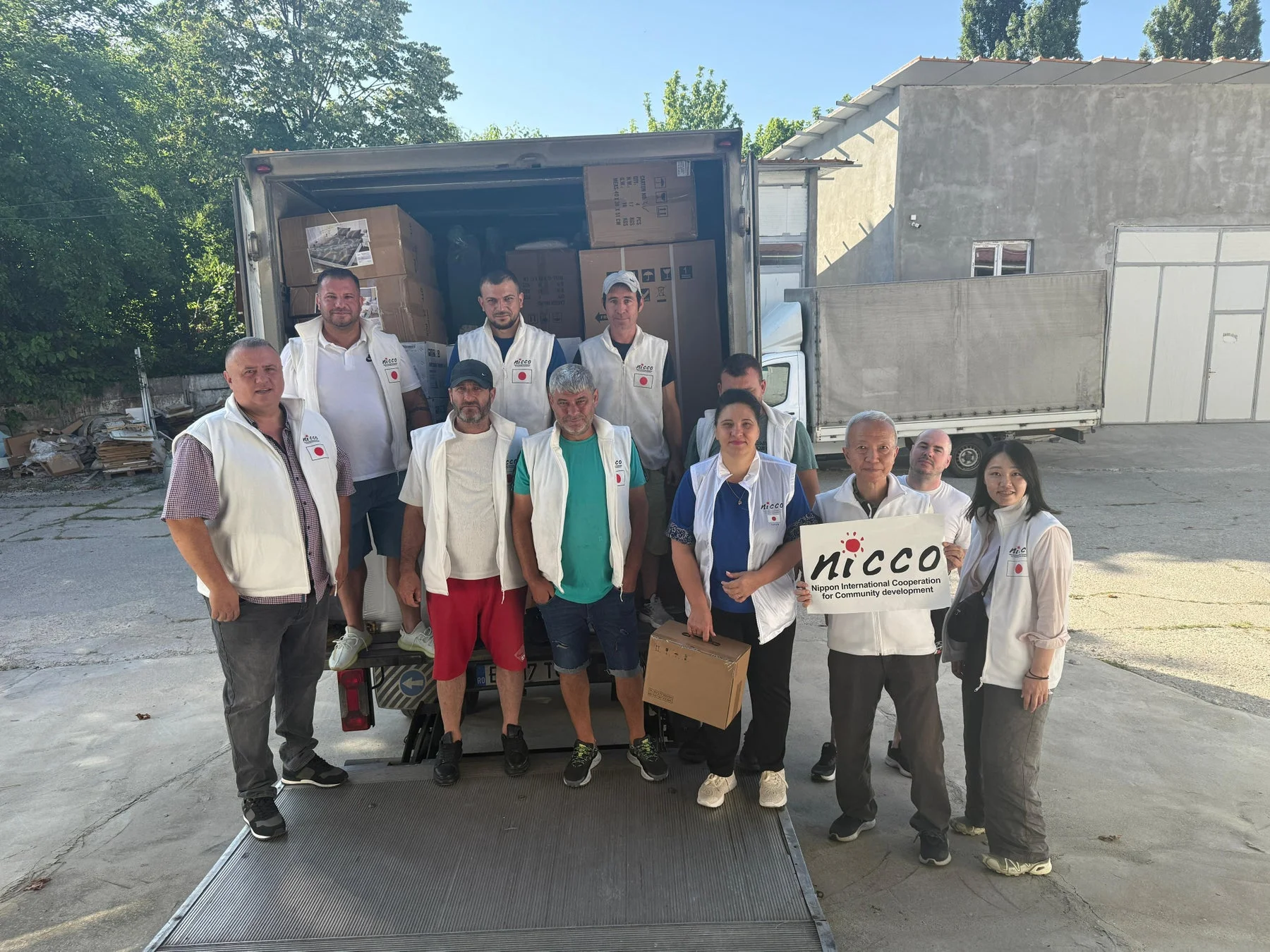 物資を積んだトラックの前でポーズをとるNICCOのスタッフたち
