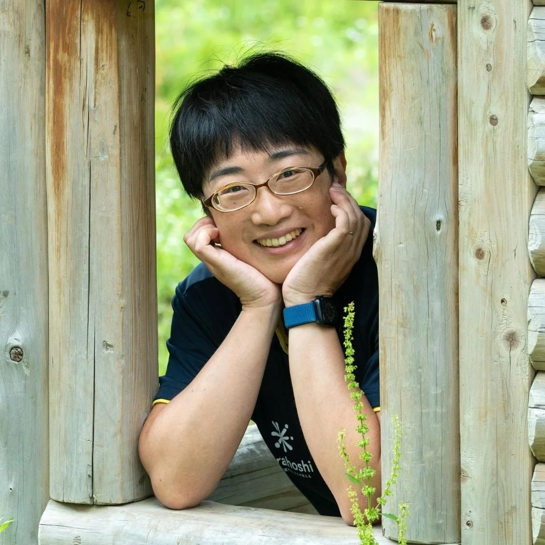 木枠から顔を出し、笑顔でこちらを見ている女性のポートレート