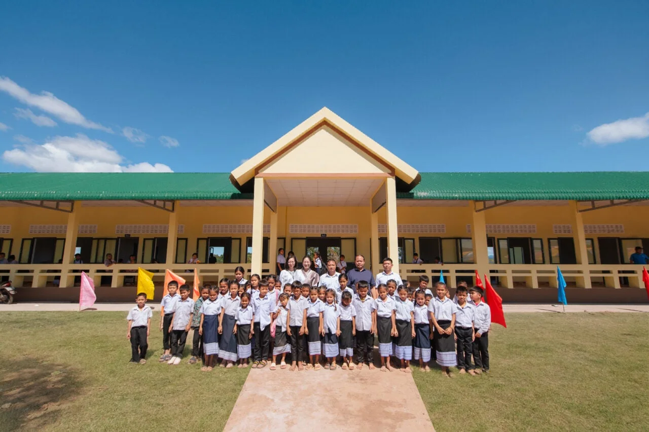 新しい校舎の前で集合写真を撮る子どもたちと大人たち