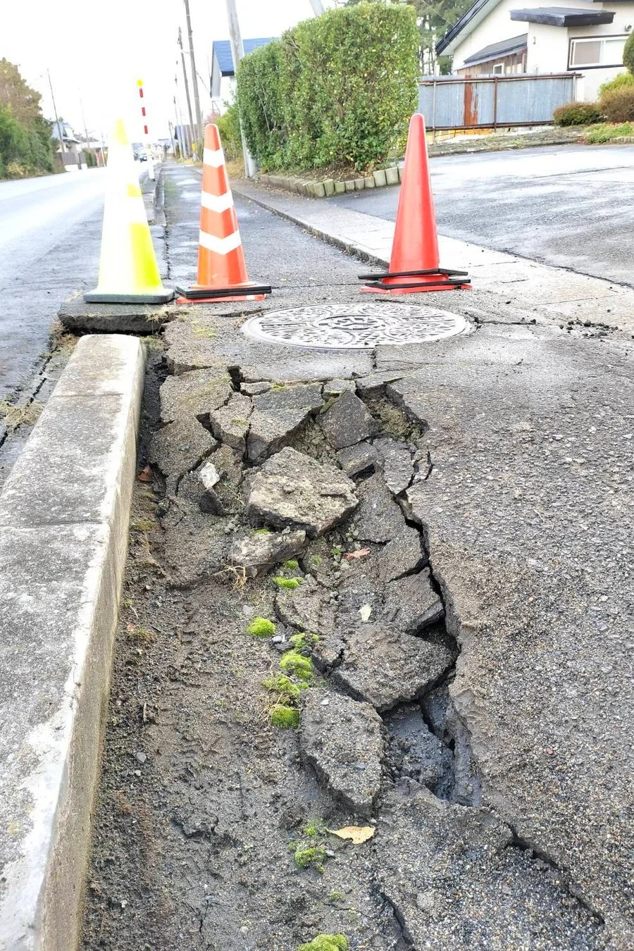 歩道と車道の境界部分のアスファルトが大きく陥没し、多数のひび割れが見られる