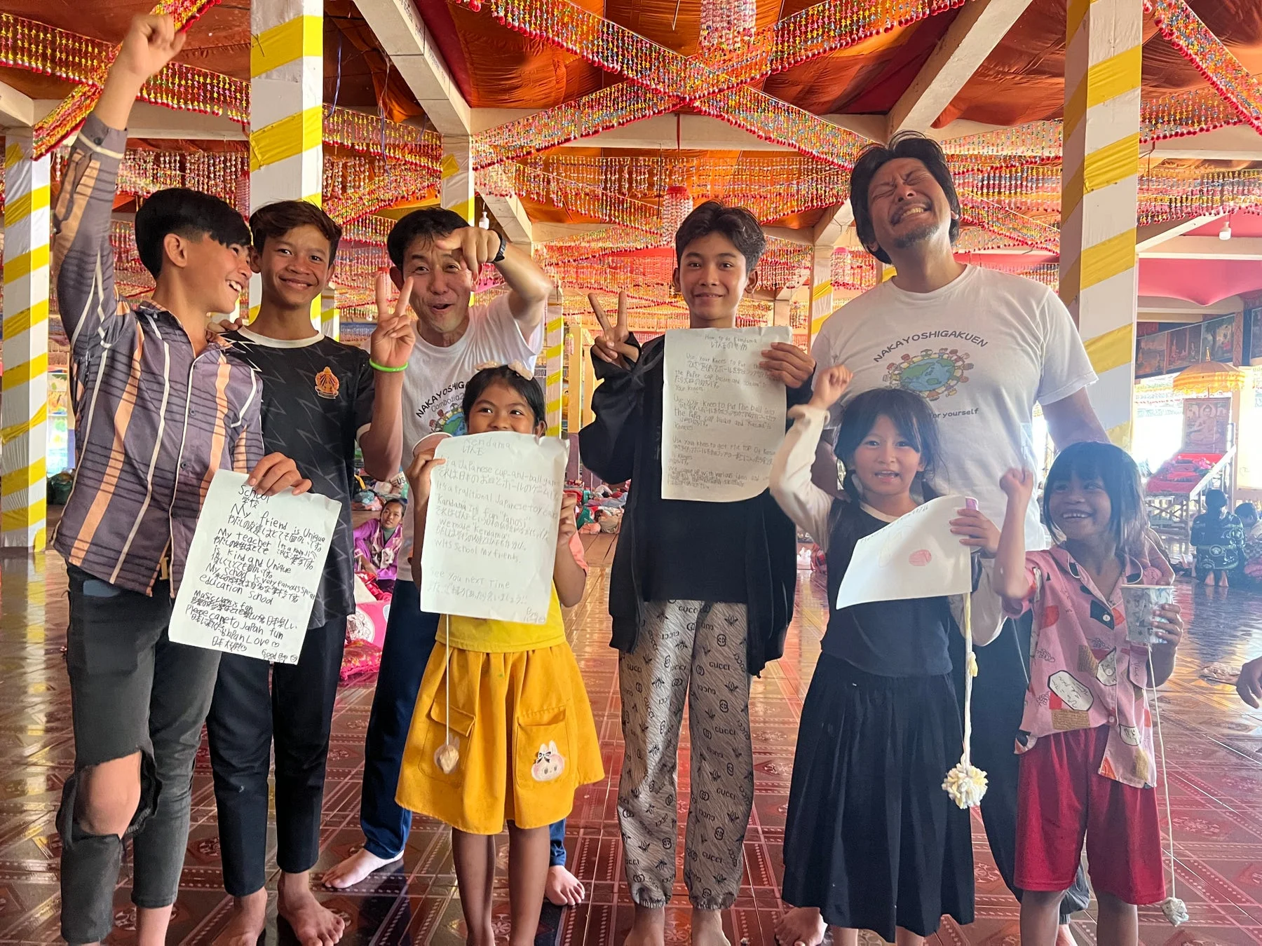 日本の伝統的な遊び「けん玉」や手書きのメッセージを通じて、子供たちと大人が楽しく交流している様子です。