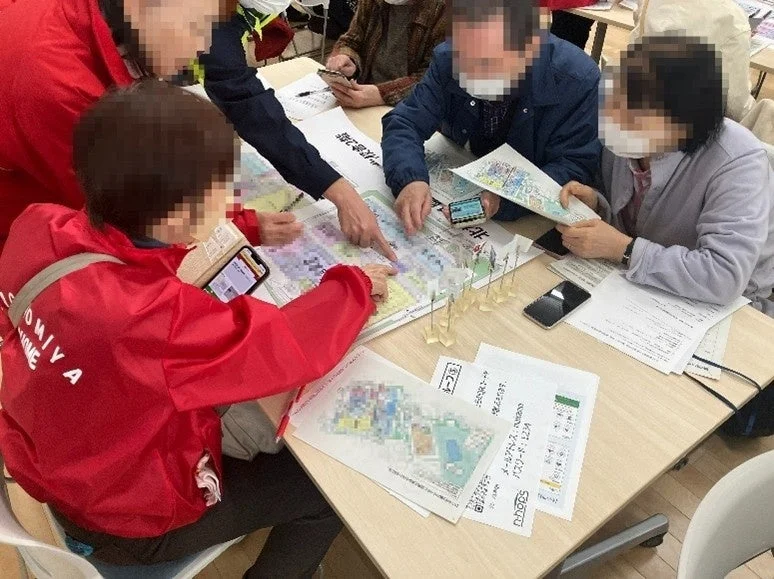 テーブルを囲んで地図や書類を広げ議論する参加者