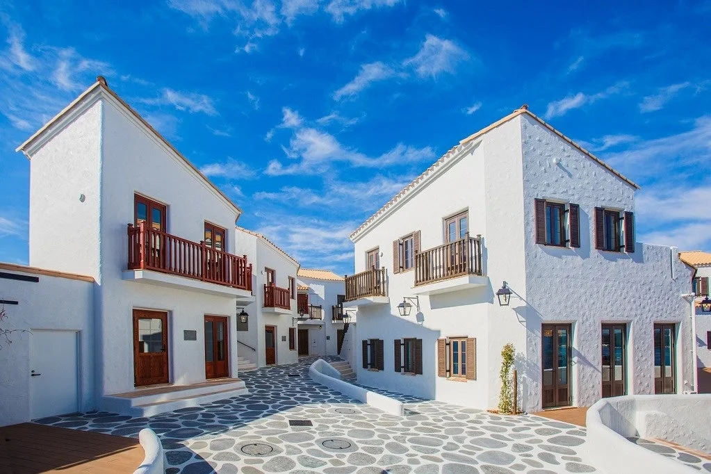 青い空と白い雲の下、白い壁の建物が立ち並ぶ美しい街並み