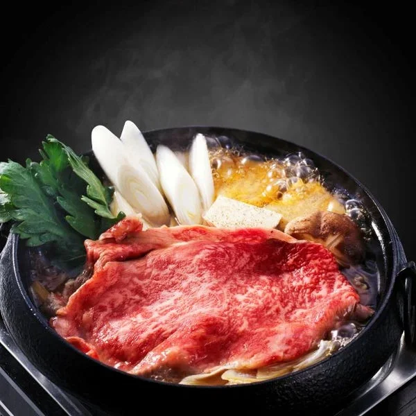 湯気が立ち上る黒い鍋に、鮮やかな霜降りの牛肉、長ネギ、春菊、豆腐、きのこなどが美しく盛り付けられたすき焼き