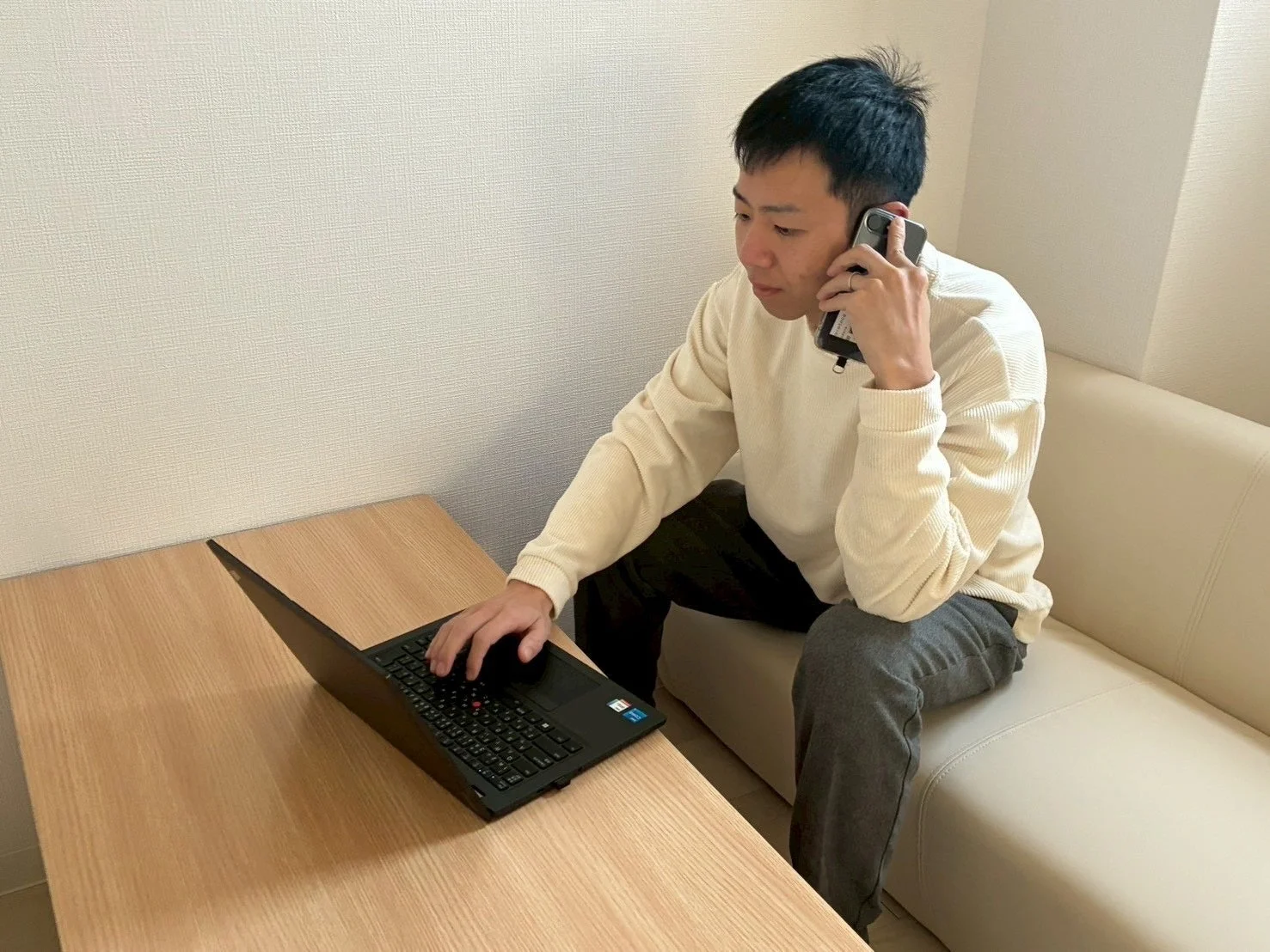 男性がソファでノートPCとスマホ