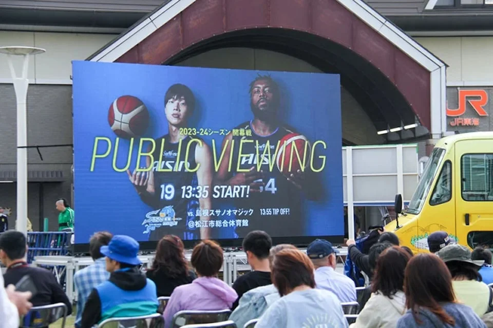 屋外でバスケットボールのパブリックビューイングを観戦する人々