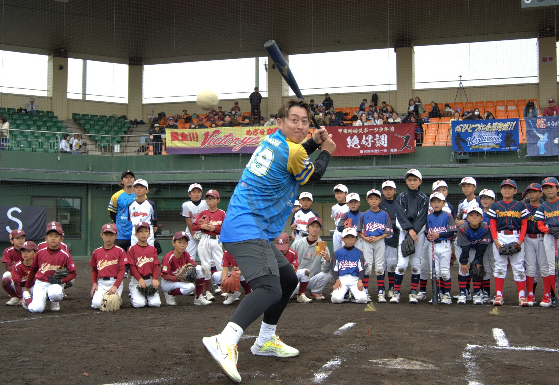野球場でバッティングを見守る少年野球選手たち