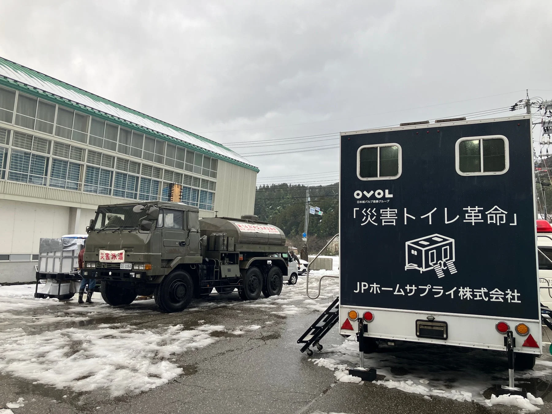 雪の中、災害支援用の給水車と災害トイレ革命号のトレーラー