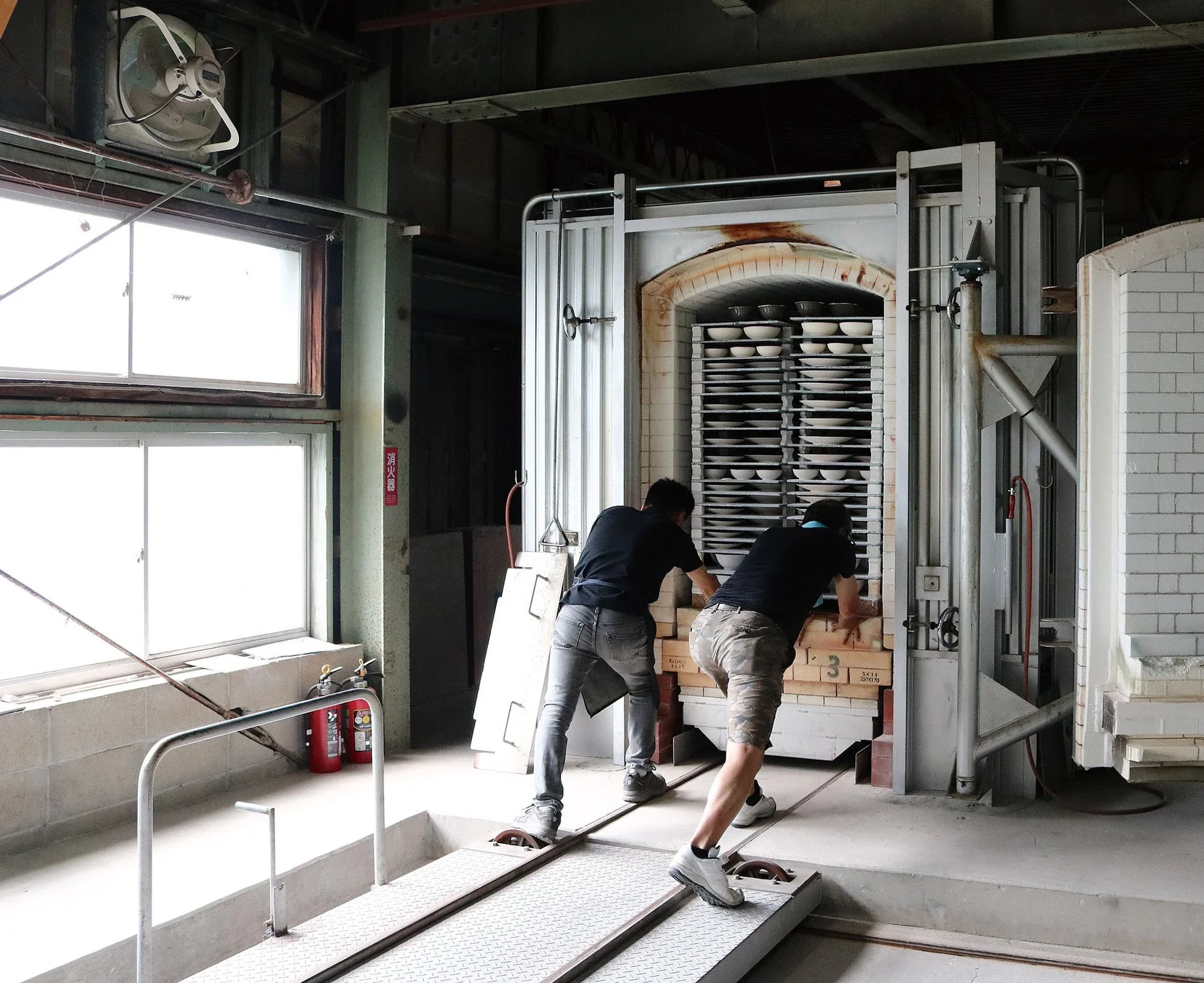 陶芸工場で職人が窯に陶器を搬入している様子