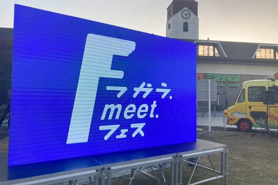 LEDディスプレイ、フードトラック、駅が見える屋外イベントの様子