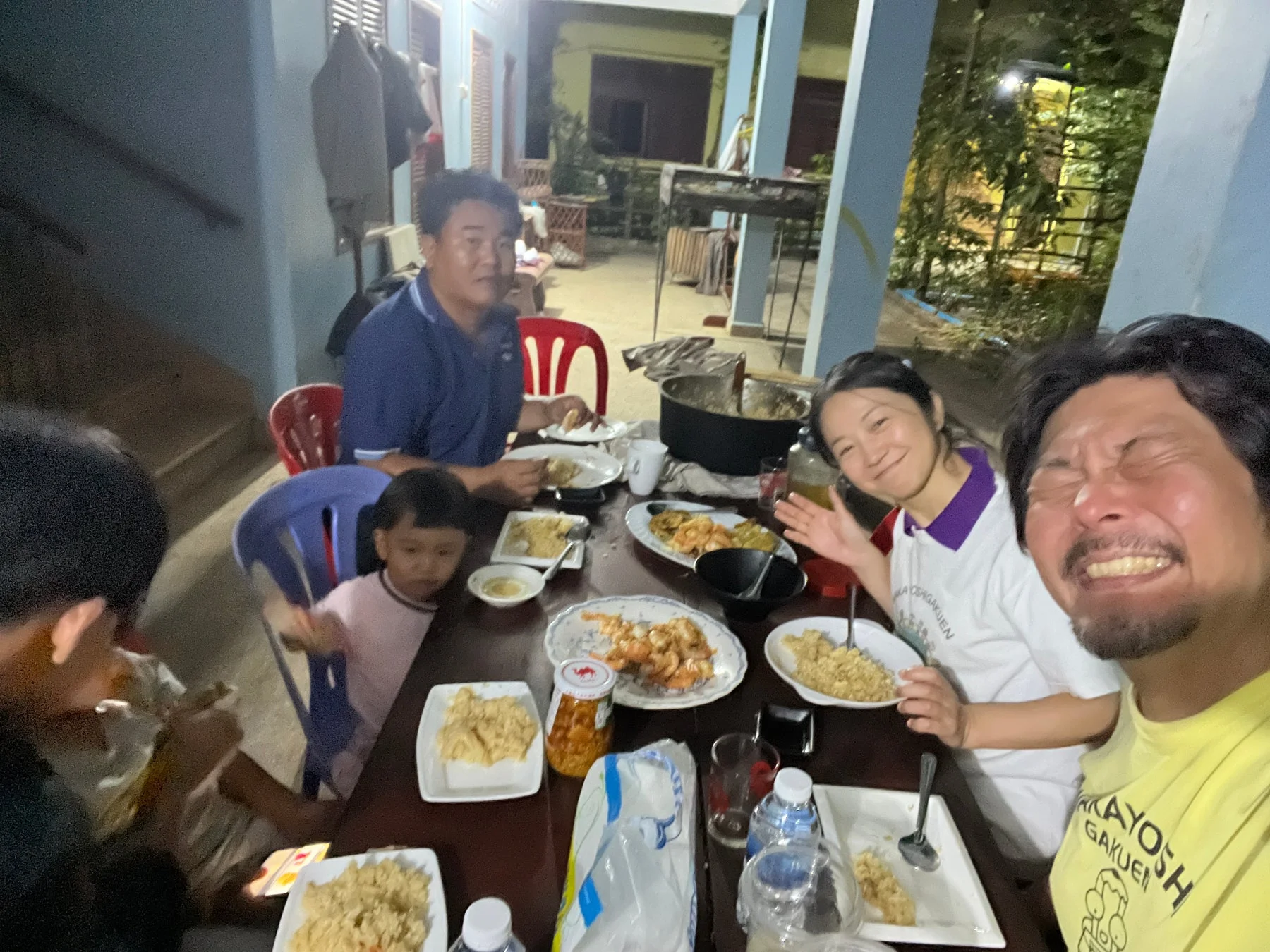 夜、屋外で大人と子供たちがテーブルを囲んで食事を楽しんでいる様子