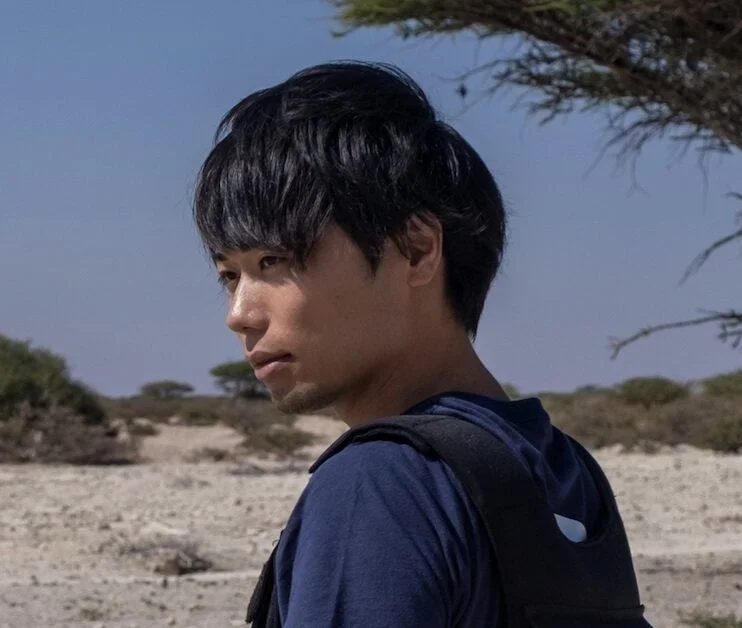 青いシャツを着てバックパックを背負った若い男性