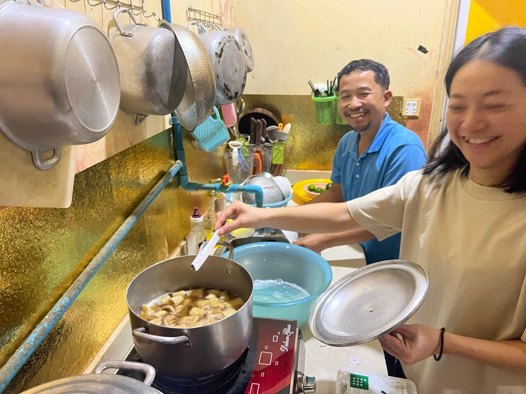 家庭のキッチンで、男女2人が笑顔で料理をしている様子