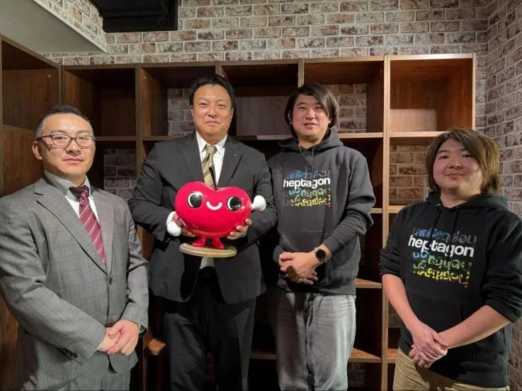 4人の男性と赤いハート型のキャラクターマスコット