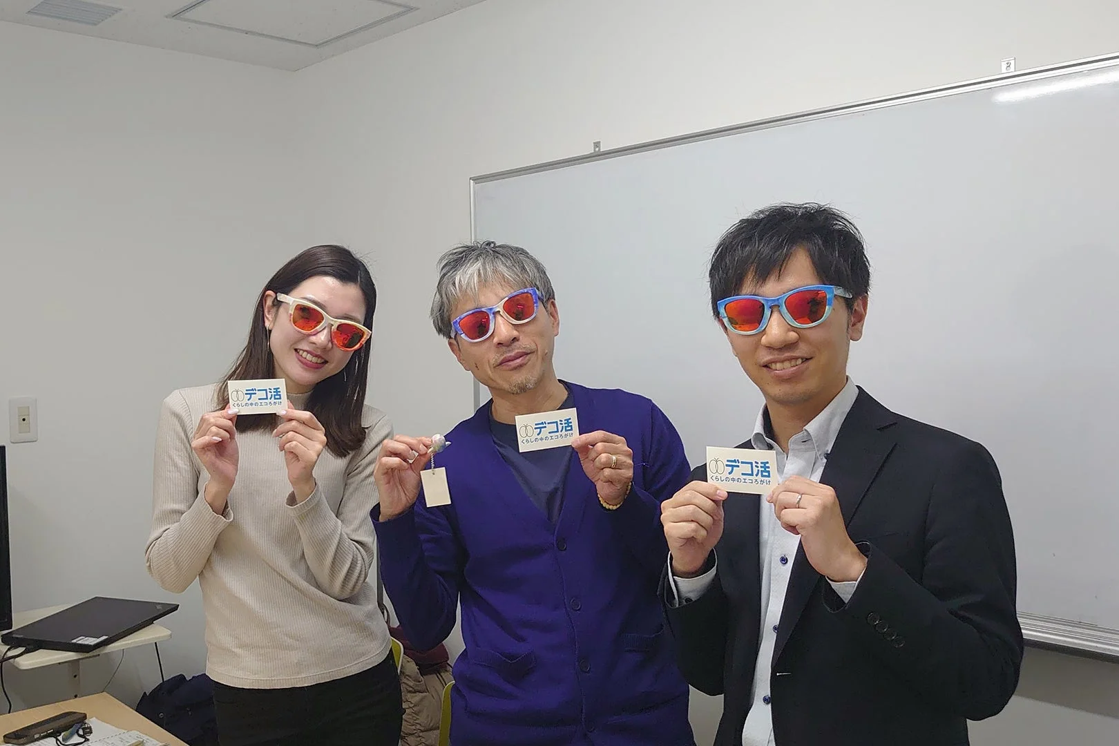 デコ活のカードを持つ人々