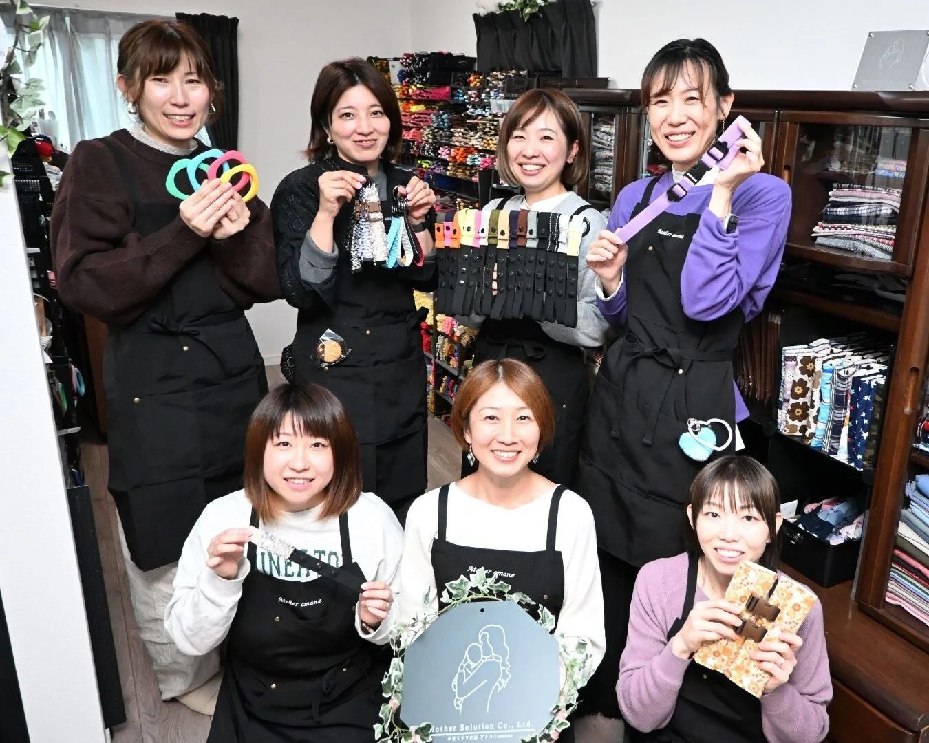 エプロン姿の女性たちが製品を持つ集合写真