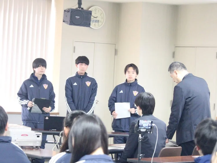 学生がプレゼンテーションを行い、大人が見守る様子