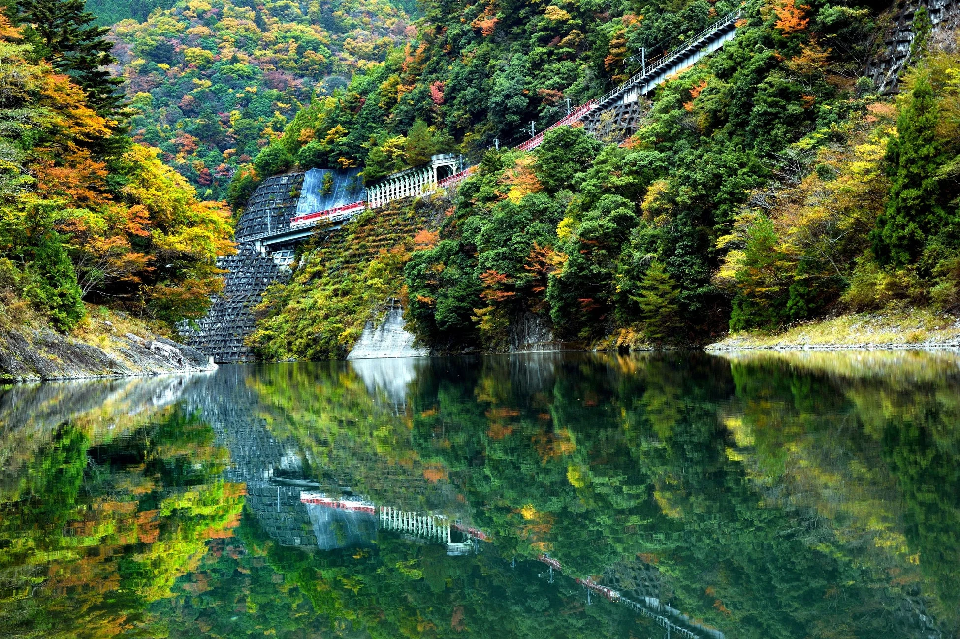 紅葉に染まる山々と、その麓を走る鉄道、そして静かに水をたたえる湖