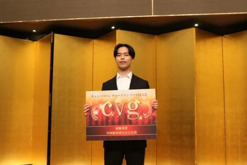 キャンパスベンチャーグランプリ中国大会で最優秀賞の賞状を掲げる男性