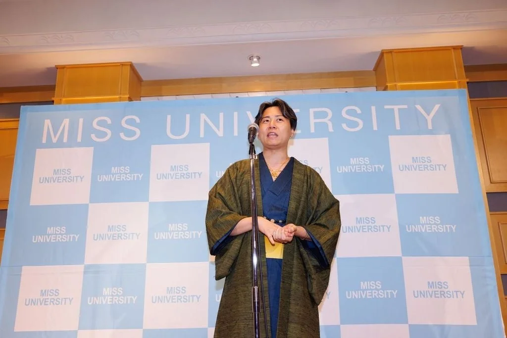 マイクを持ってスピーチをする和装の男性