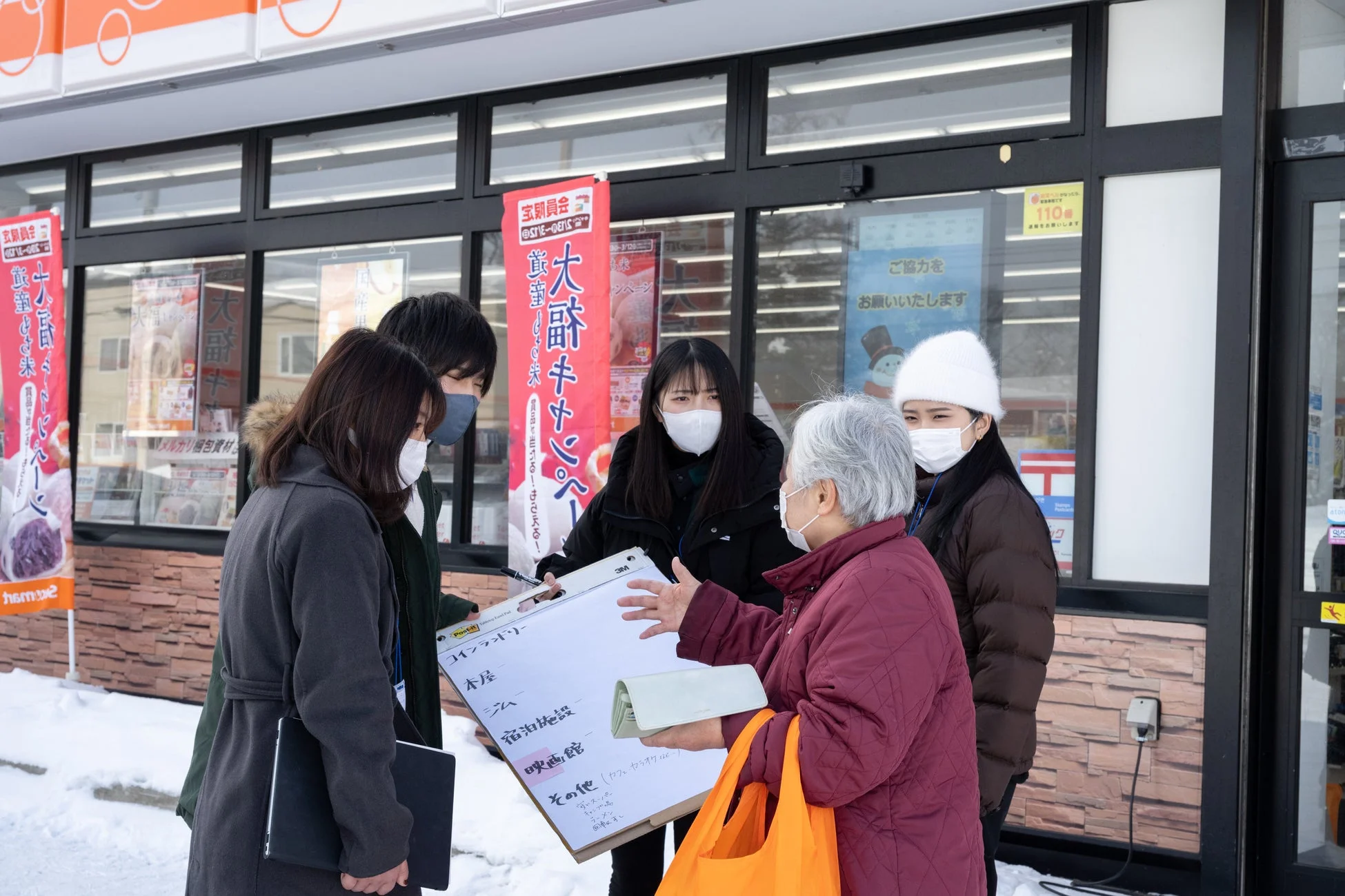 雪の中で住民と話す学生たち