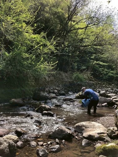 小川で水を汲む人