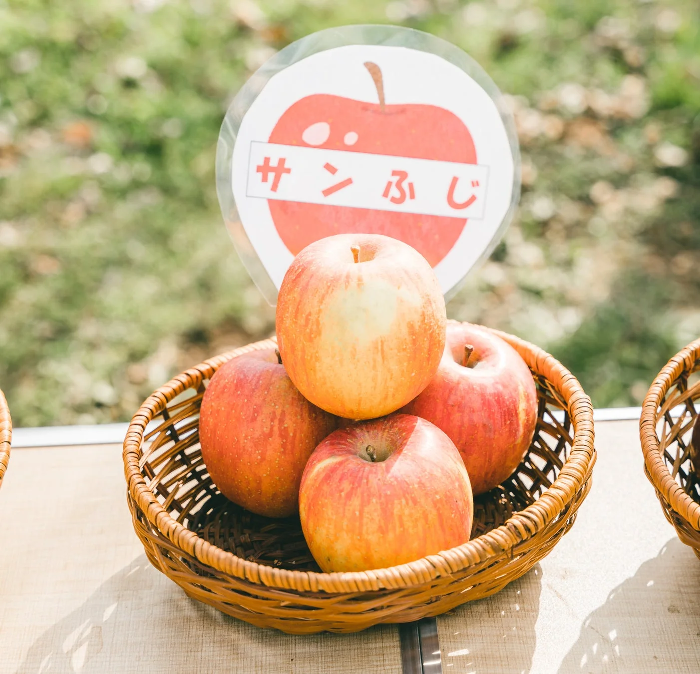 籐のバスケットに盛られた赤と黄色のサンふじりんご