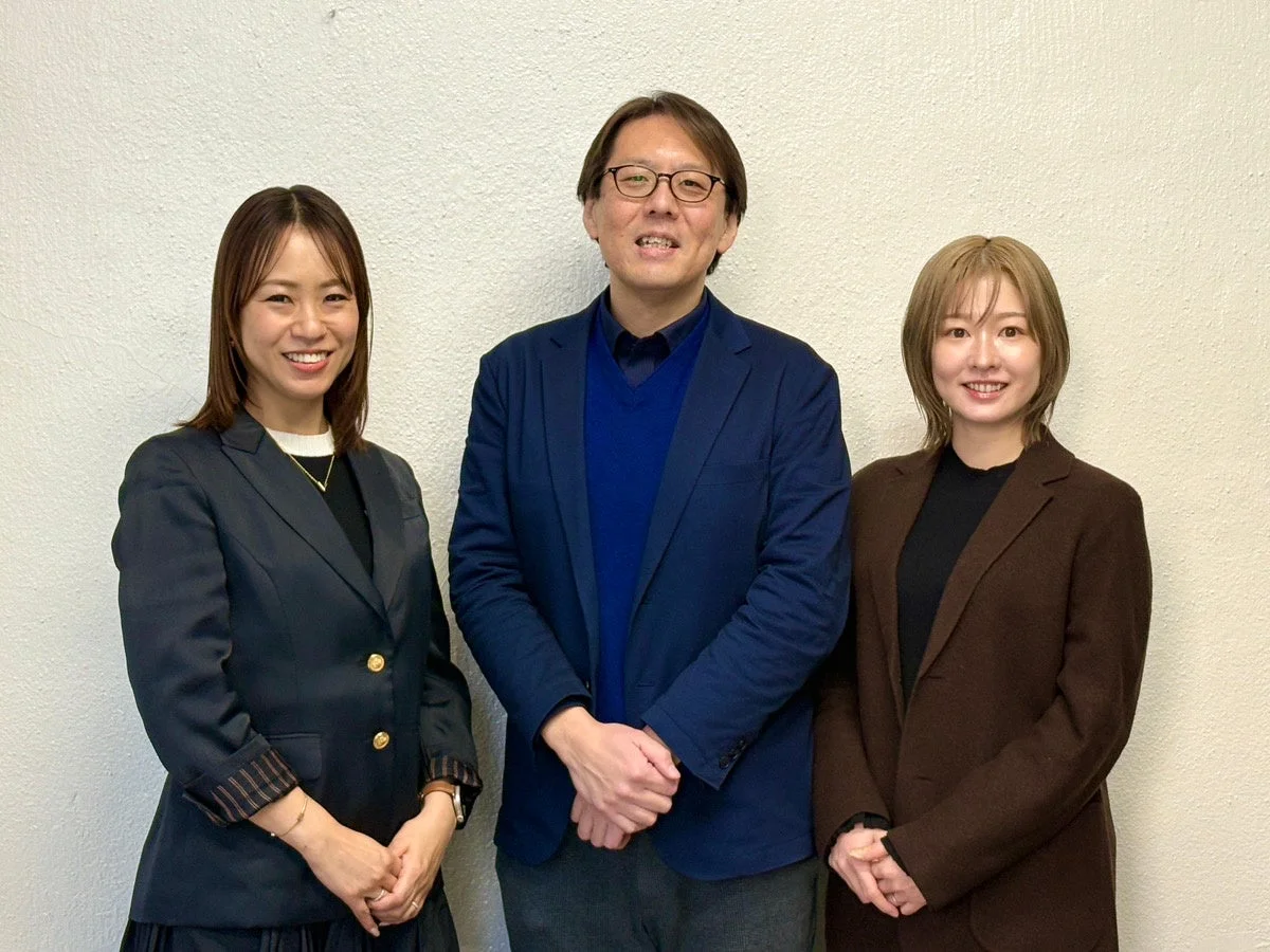 3人のビジネスパーソンが笑顔で並ぶ