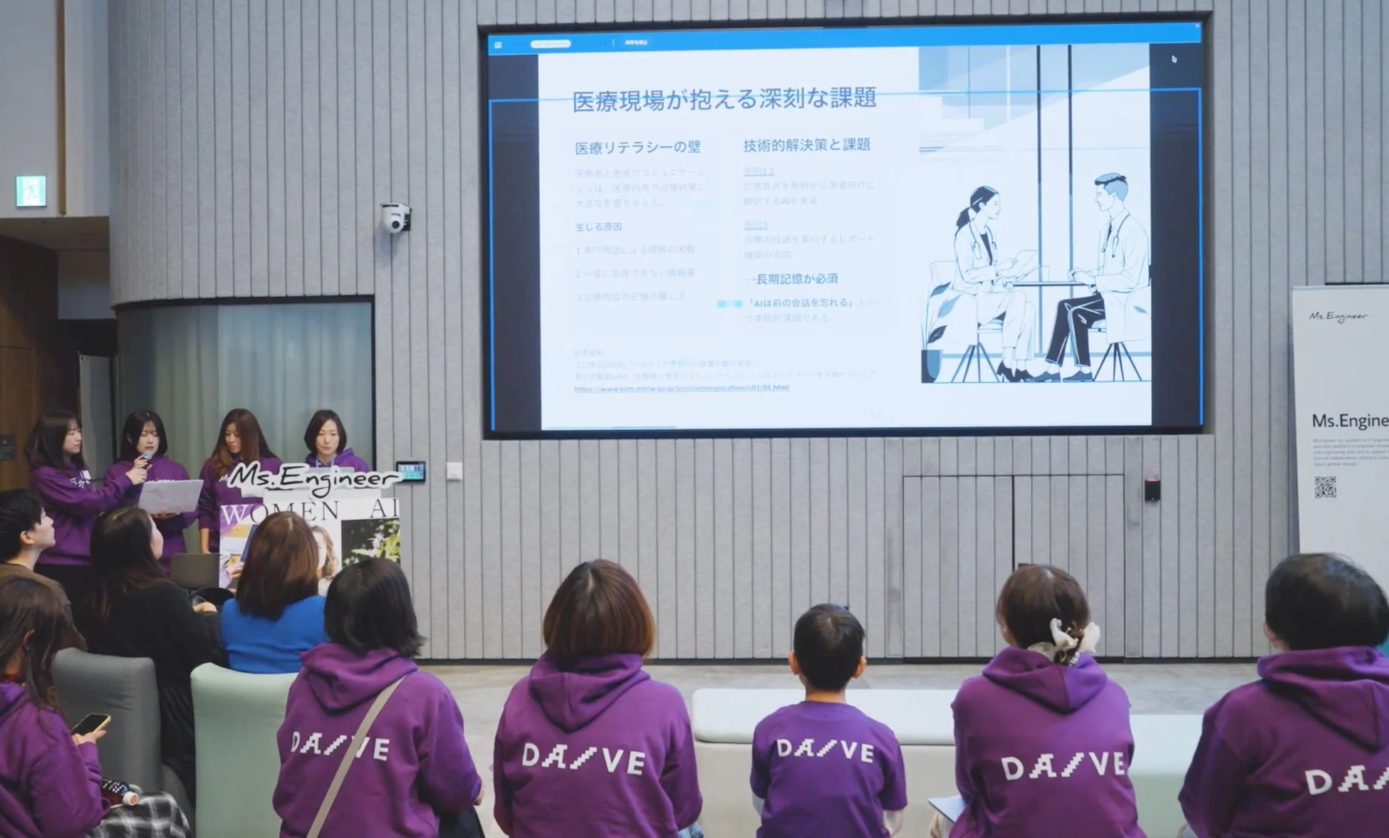 医療現場の課題とAIによる解決策についてのプレゼンテーションを聞く聴衆の女性たち