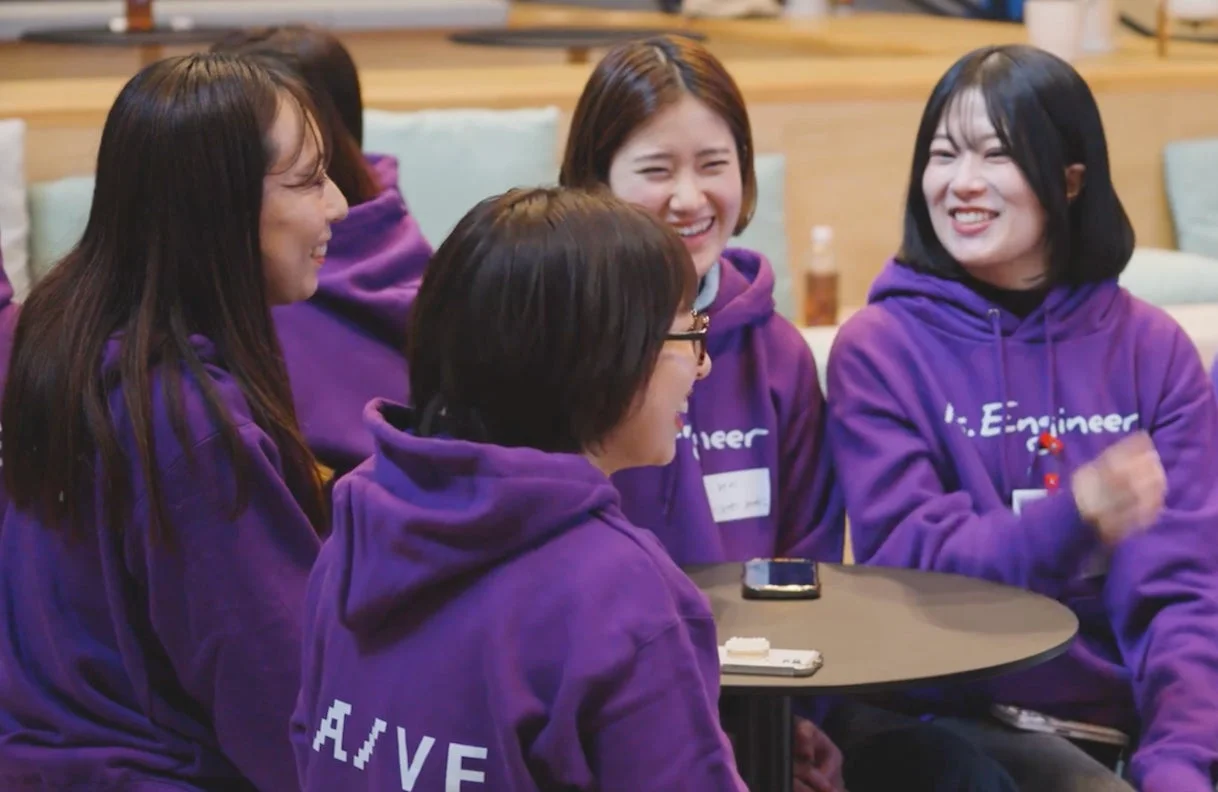 紫のパーカーを着た女性たちが楽しそうに会話している様子