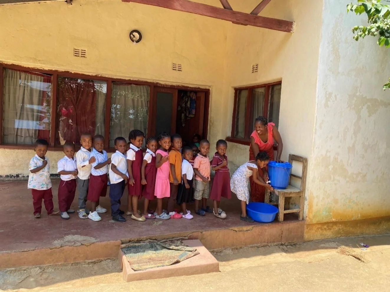 屋外で手洗いをする多くの子供たち