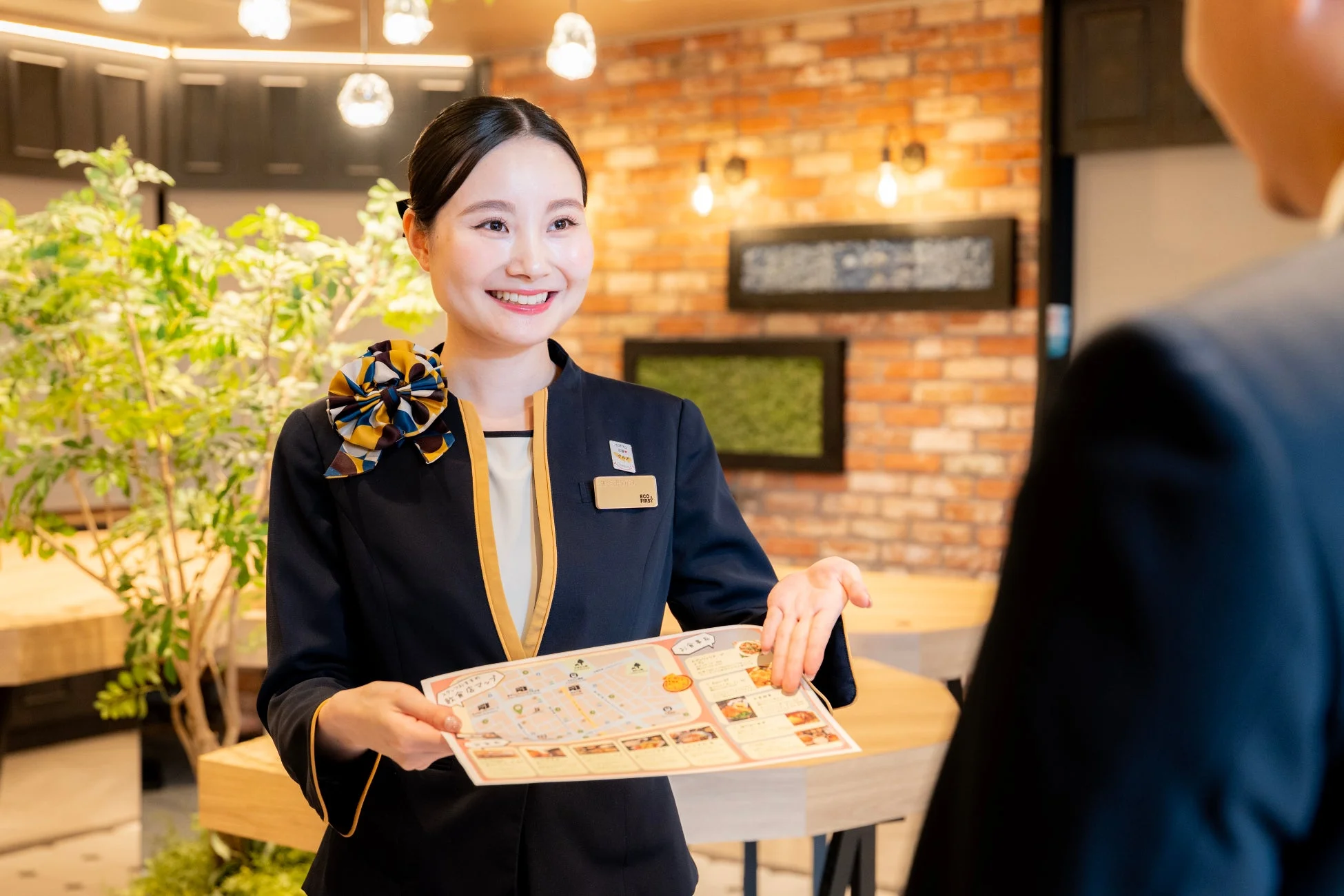笑顔の女性スタッフが飲食店舗マップを手に顧客に案内