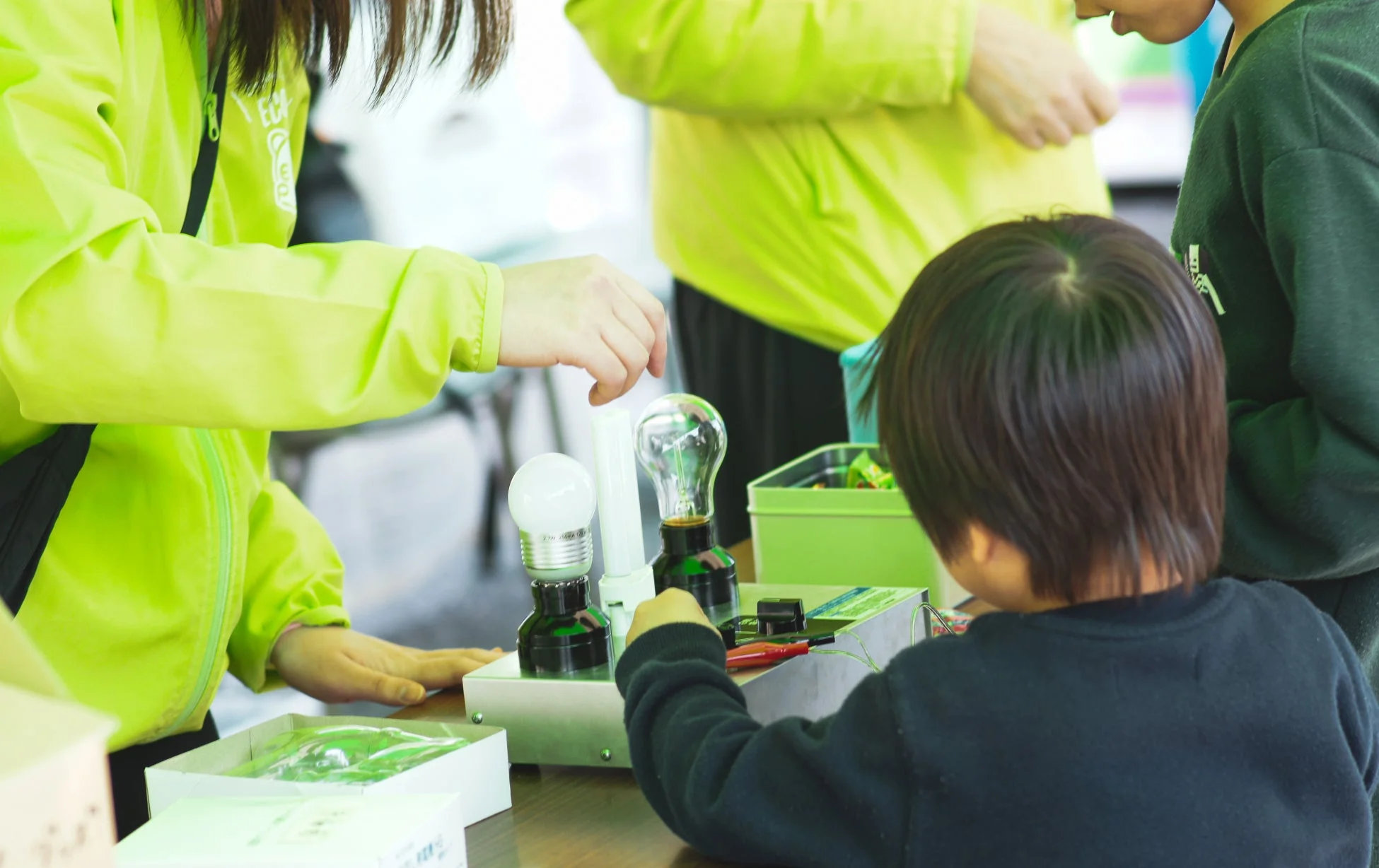 子供と大人が電球を使った科学実験を行っている様子