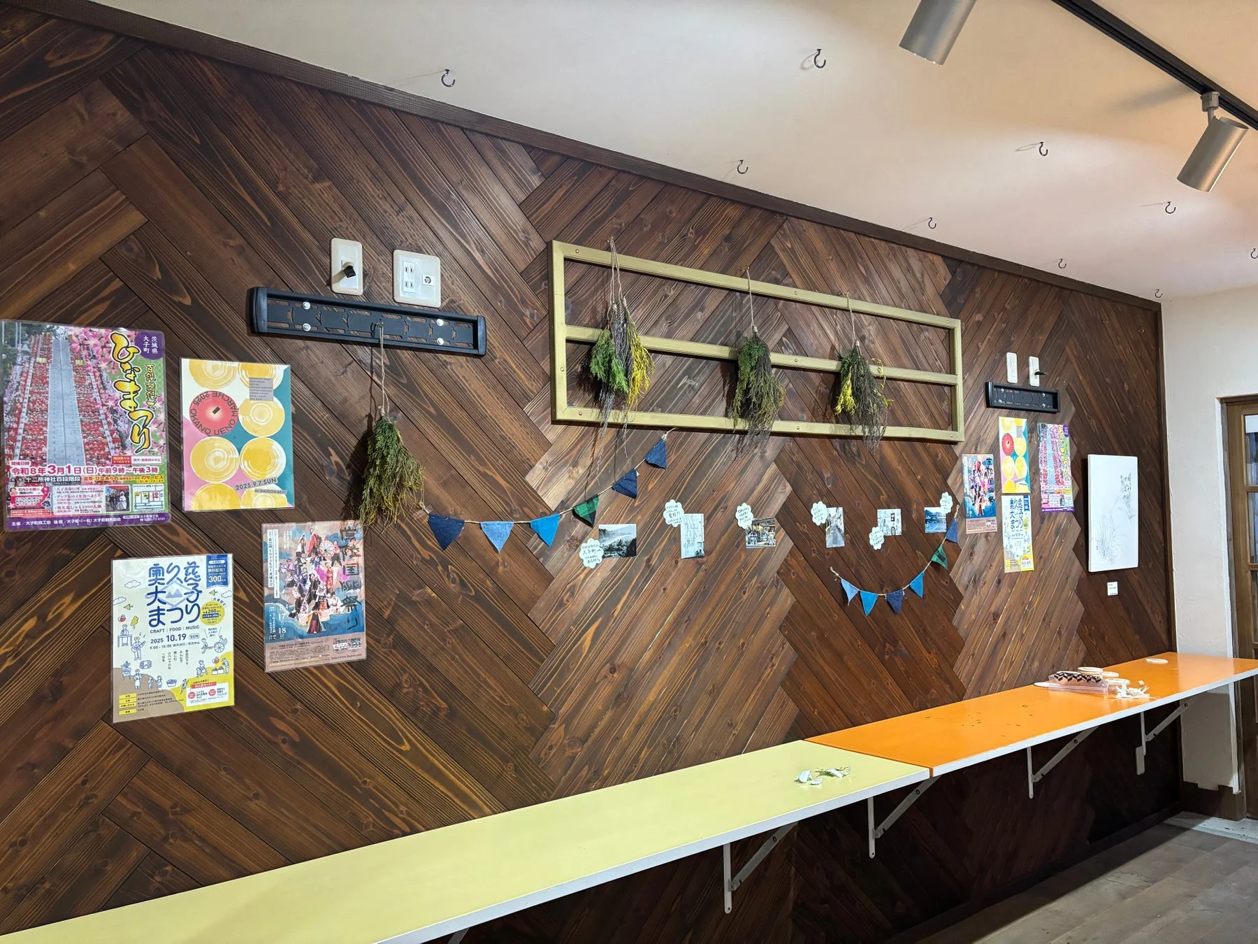 木目調の壁にイベントポスターや飾り付けがされたカフェ風の空間