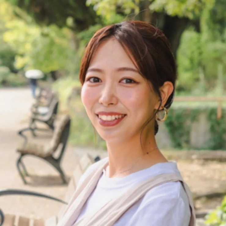 公園のような屋外で笑顔を見せる女性