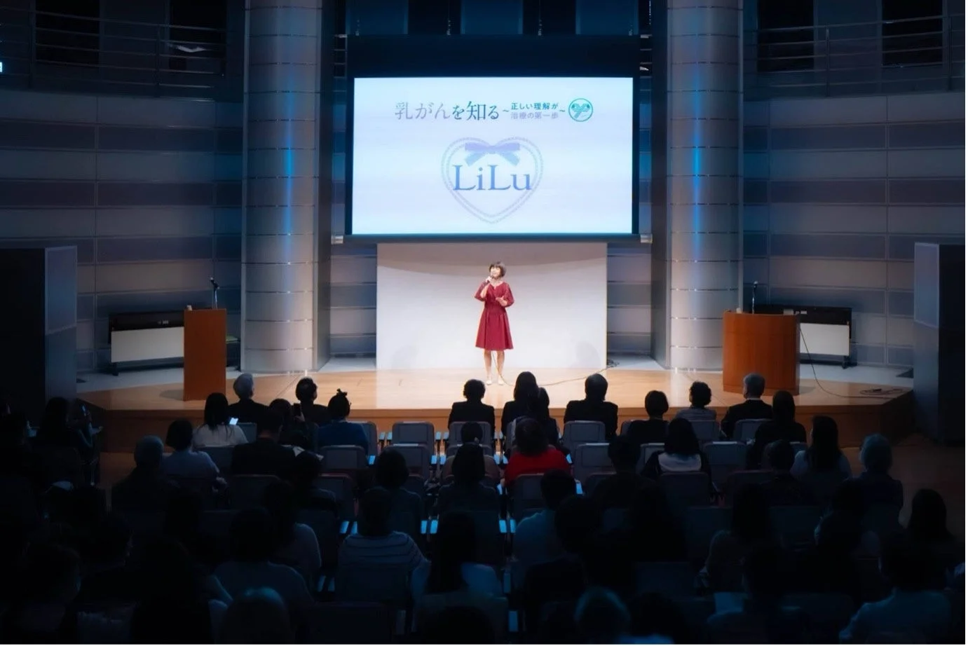 ホールで女性が乳がんに関する講演を行っている