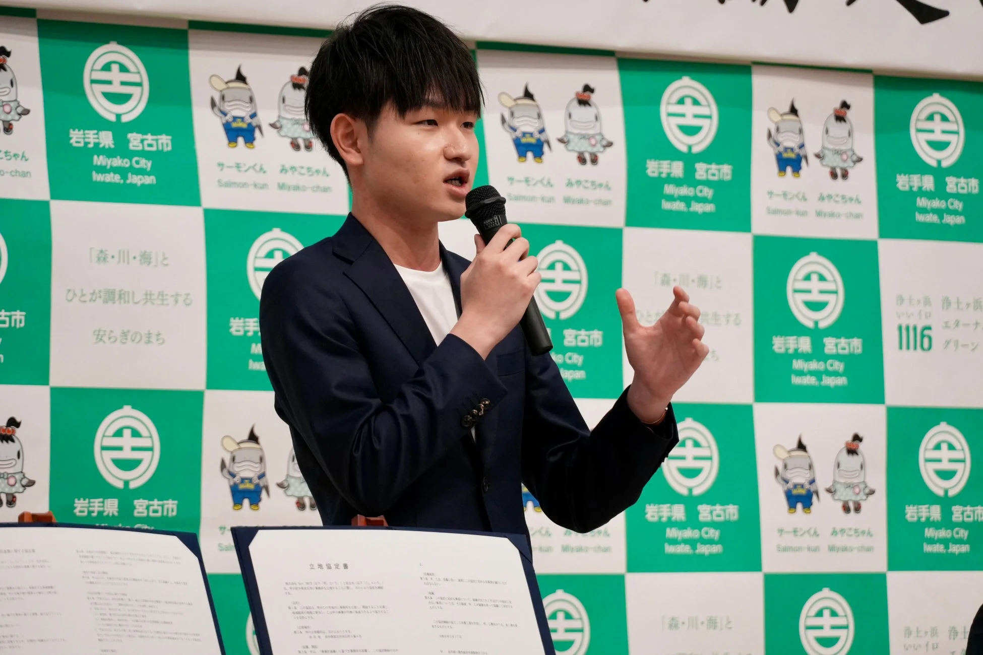 協定書を前に話す男性