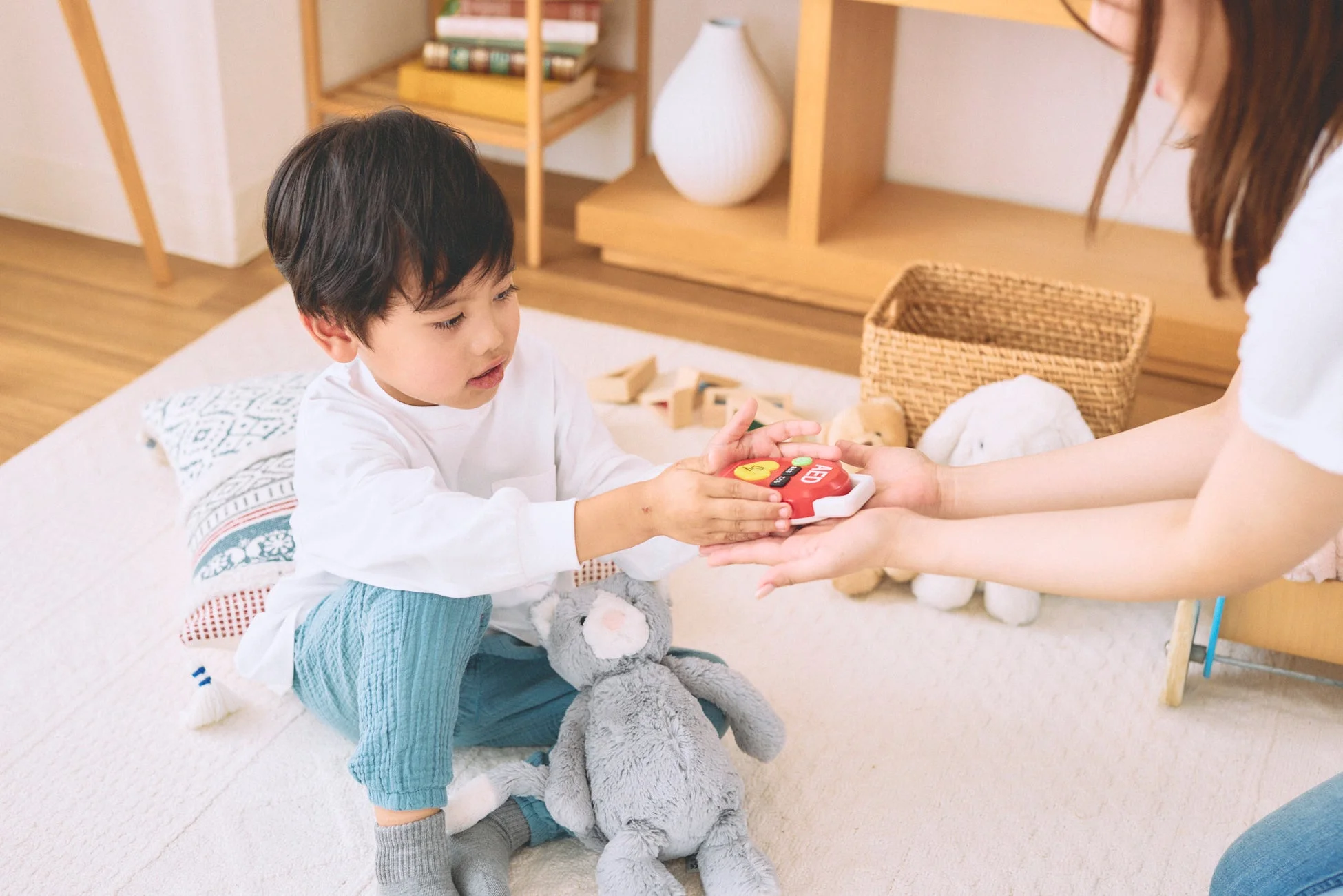 子どもと大人がおもちゃのAEDで遊ぶ様子